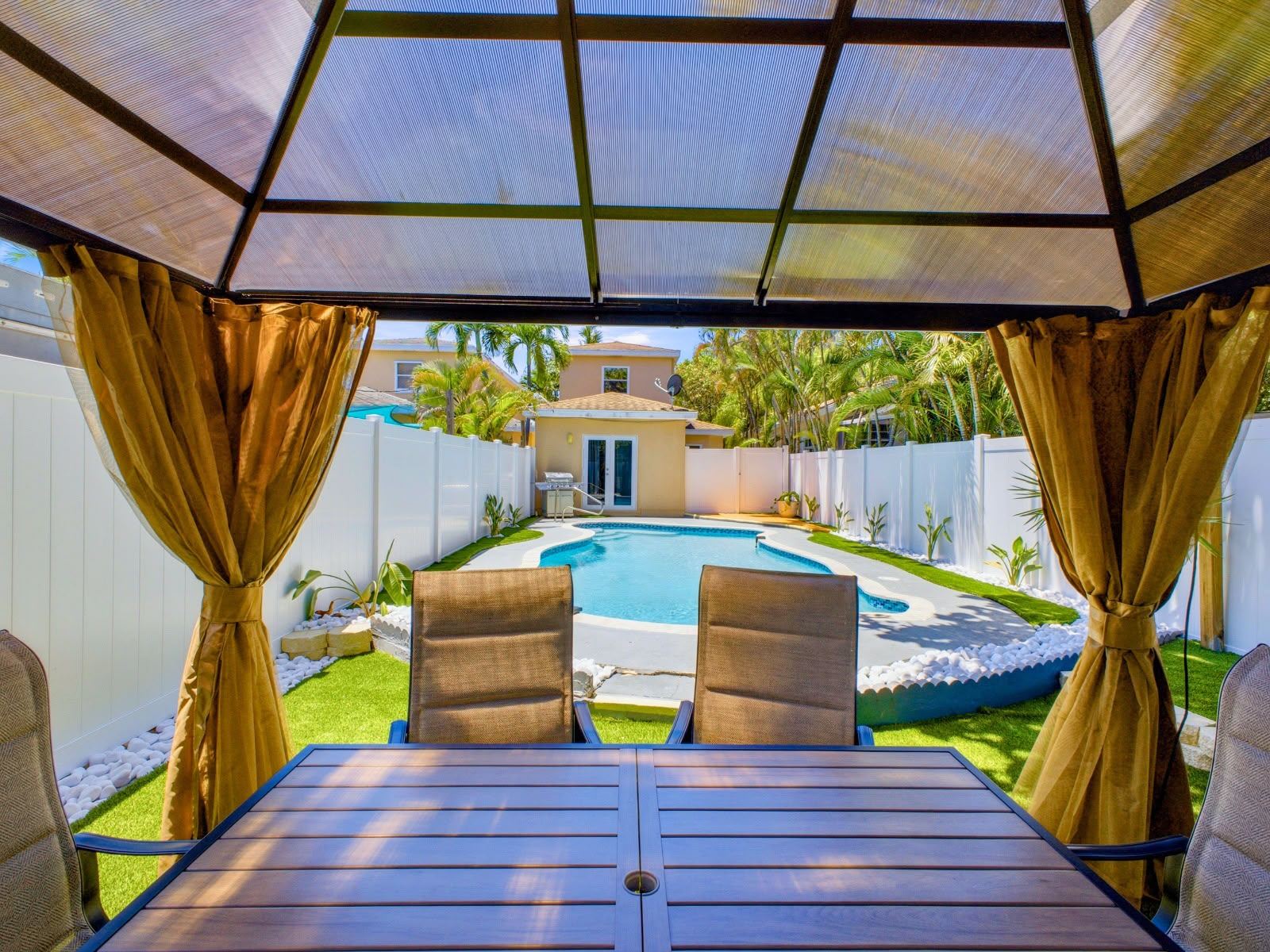 Pool cabana with outdoor dining table and curtains